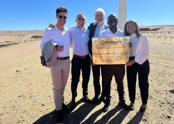 WhatsApp Image 2026-10-27 at 175214 | Mining and Energy Namibia | Namibia’s Leading Mining & Energy News Five professionals stand together outdoors at a wind farm, smiling and holding a commemorative plaque for Innovent Wind Farm.